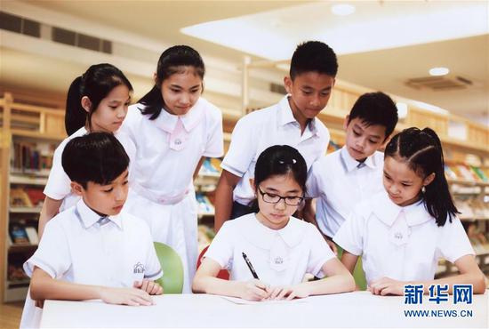 澳门濠江中学附属英才学校的小学生在写信（随信附赠的照片）。新华社发