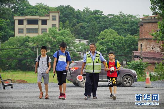 江西省上栗县彭高镇东山村的李丙味（右二）带领孩子们过马路（5月30日摄）。新华社记者 周密 摄